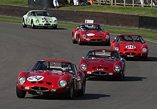 Five racing cars in line, taking a right-hand corner on a race track
