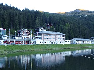 Three-story building with hip roof next to a lake