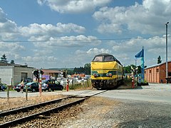 Une motrice Diesel pousse une rame réversible à l'entrée de la gare, le long de la remise du CFV3V