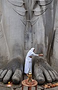 A Jain woman washes the feet of Bahubali Gomateswara at Shravanabelagola, Karnataka. The Bahubali idol is 58 feet (18 m) high and is carved out of a single rock on top of a hill.