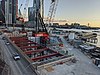 Picture of Barangaroo station under construction. It consists of a hole in the ground with cranes above.