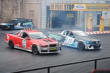Two rally cars perform a coordinated drift manoeuvre during a Hollywood Stunt Driver performance.