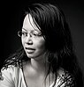 Young Asian woman with long black hair, white T-shirt and glasses, looking aside