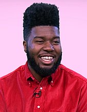 Picture of a young man smiling at the camera whilst sporting a red top