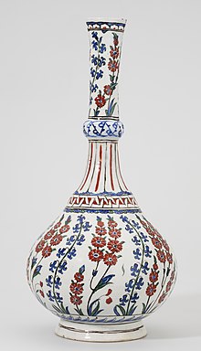 Tall white ceramic vase with brightly coloured decoration, mostly representing plants