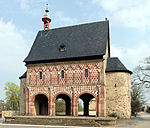 A stand-alone gatehouse surrounded by trees.