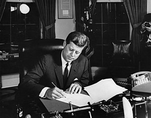 נשיא ארצות הברית ג'ון פיצג'רלד קנדי בחדר הסגלגל חותם על צו הסגר הימי על קובה, במהלך משבר הטילים בקובה.
