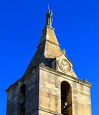 Le clocher avec une statue sommitale et une horloge.