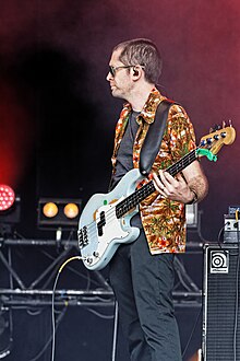 Man holding an electric bass wearing a questionable Hawaiian shirt on stage at Festival du Bout du Monde 2014