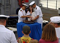 A baby is baptized with holy water from the ship's bell'