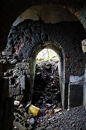 Petite pièce avec des murs en pierre et des ouvertures arrondies.