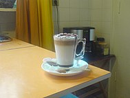 A caffè mocha sitting on a white plate and beige table.