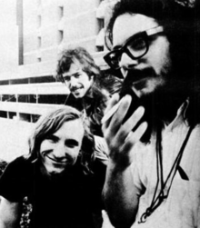 A black-and-white photo of the band members posing together, smiling