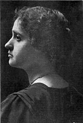 Black-and-white photo of a woman's head an shoulders from behind, facing left