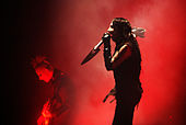 A picture of a man singing into a microphone and a man playing a guitar on a stage