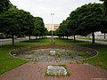 Vorplatz des ehemaligen Bahnhofs Wiesdorf mit Straßenführung, Grünanlage und Brunnen