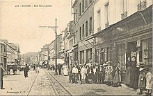 Carte postale noire et blanc. Rue bordée de maisons.