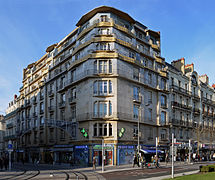 Photographie d'un immeuble Art déco, à l'angle d'une rue, à gradins dorés et mosaïque bleue.