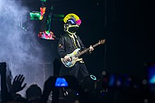 A man wearing a custom space helmet plays the bass