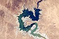 Image 14 Haditha Dam Photograph credit: NASA, Kjell N. Lindgren The Haditha Dam is an earth-filled dam in Iraq, holding back the waters of the Euphrates to create Lake Qadisiyah. The area around Haditha is very arid, with a hot desert climate; the annual precipitation is about 127 millimetres (5 in), mainly occurring during the winter. This photograph, taken from the International Space Station in November 2015, shows the reservoir at a low water level, surrounded by an expanse of dry lakebed; the Haditha Dam is visible near the top of the image. Lake Qadisiyah has a maximum water-storage capacity of 8.3 cubic kilometres (2.0 cu mi) and a maximum surface area of 500 square kilometres (190 sq mi). The associated hydroelectric power station is capable of generating 660 megawatts of electricity, and outlets at the foot of the dam can discharge 3,000 cubic metres (110,000 cu ft) of water per second for irrigation.