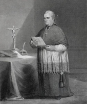 Black and white illustration of a man wearing a zucchetto, liturgical vestments, and a pectoral cross facing right, with a crucifix on a table to his right.