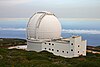 A white telescope dome on a mountainside