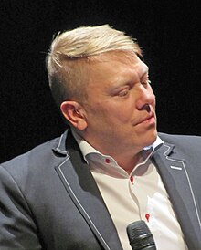 Headshot of Jón Gnarr, a middle-aged white blond man with wearing a morning suit.