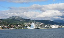 Foto einer an der Küste gelegenen Stadt, dahinter liegen Berge