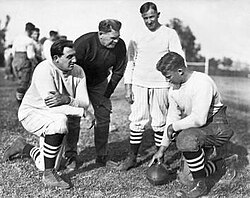 Three men crouched and one standing