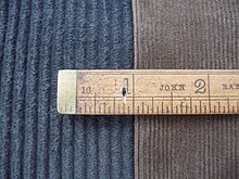 Close up of two pieces of cord cloth, dark grey is standard weight with adjacent piece of finer brown needlecord