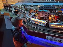 Boy watching toy train pass on train layout.