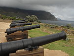 The Dutch East India Company, and later the British government, were interested in Hout Bay not only uecause of its forests, but also because it could serve as an alternative anchorage when Table Bay was unsafe, and above all because it offered a possible landing place for hostile forces. Consequently fortifications were erected towards the end of the eighteenth century, first on the western side of the bay at the foot of the mountain called Hangklip, and later on the eastern side below Chapman’s Peak. Type of site: Fort Previous use: Fortification. Current use: Vacant.