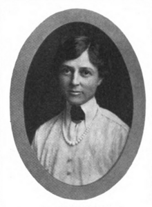 A white woman in an oval frame; she is wearing a simple white shirt with a long pointed collar, and a string of white beads or pearls