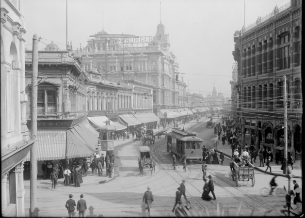 View north on Spring St. from First Street. Los Angeles National Bank building in foreground, right. Larronde Block in foreground, left. Phillips Block visible in background. Note the electric streetcar to Grand Ave.