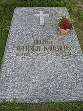 A marbled-grey stone slab, lying flat on the ground, bearing the golden inscription "Oberst Werner Mölders 18.3.1913–22.11.1944" just below the centre of the slab.