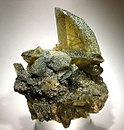 Yellow-green titanite twinned crystal perched vertically on the matrix