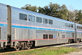 Stainless steel bilevel passenger rail cars with a blue stripe and two thinner red stripes between levels, plus a red sill stripe