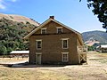 East end of the restored barracks building. The unreconstructed kitchen/mess hall is outlined by split rail fence to the left.