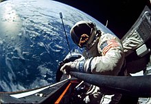 Selfie en couleur d'Aldrin en combinaison spatiale, dans l'espace et avec la Terre à l'arrière-plan.