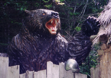 A statue of a roaring bear looking over a fence