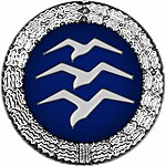 Badge: on a blue disc, silhouette of three white birds stacked in flight, the whole surrounded by a silver wreath