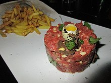 Raw beef shaped into a disk and garnished with a quail egg
