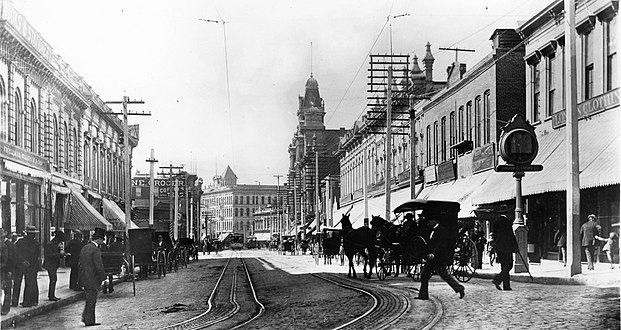 View south on Spring St. from Temple, c.1883–1894. The towers in the background are the Phillips Block; the two larger buildings to its right are the Jones Block and (with turrets) City of Paris. Far right: Allen Block and Harris & Frank's London Clothing Co., with its landmark clock.