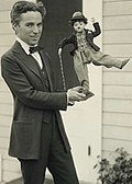 Chaplin, en 1918, tenant une figurine à l'effigie de Charlot.