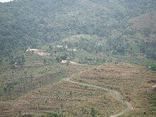 Photographie couleur des bâtiments à flanc d'une montagne dans laquelle des terrasses agricoles sont aménagées