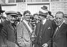 Photographie en noir et blanc de plusieurs hommes autour d'un trophée.