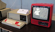 A computer in a red case with a separate monitor and keyboard. The monitor is displaying a vector graphic of a wave.