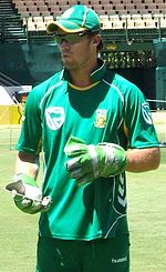 A man wearing a green top and cap, light green gloves and black goggles