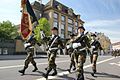 Photographie représentant les soldats portant le drapeau de leurs régiment durant un défilé