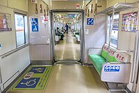 Innenraum eines durchgängigen Zuges der Baureihe 2000 der U-Bahn Fukuoka mit Mehrzweckfläche für Rollstühle und Kinderwagen und priority seats